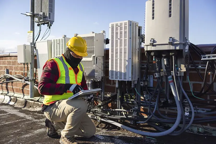 Técnico en una azotea trabajando en equipo HVAC mientras sostiene una tablet.