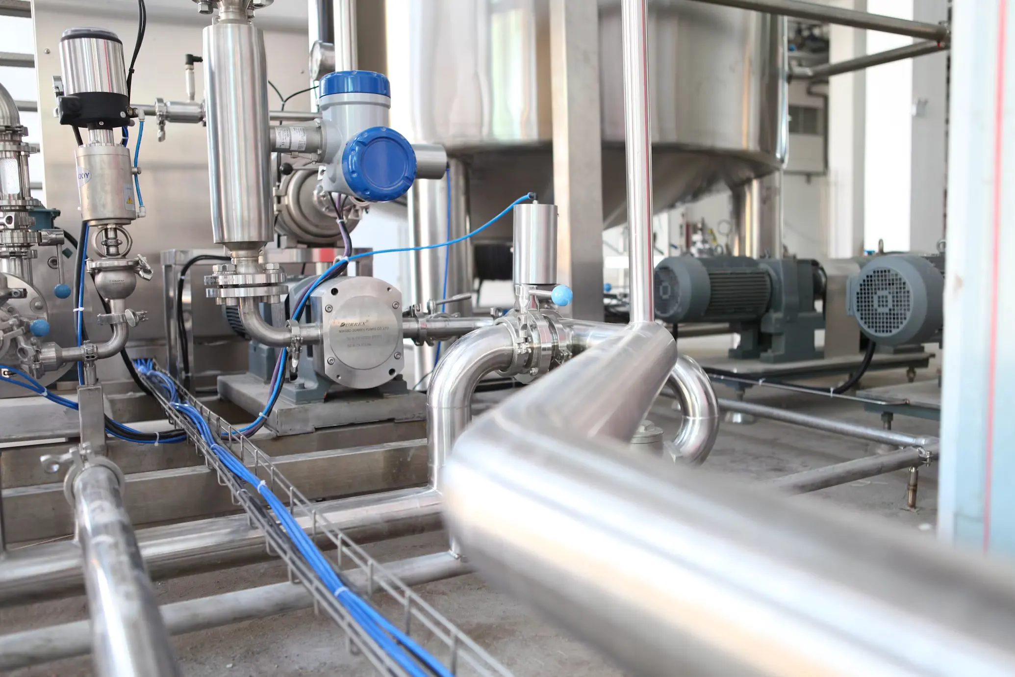 Industrial pump room interior with stainless steel piping, valves, and motors.