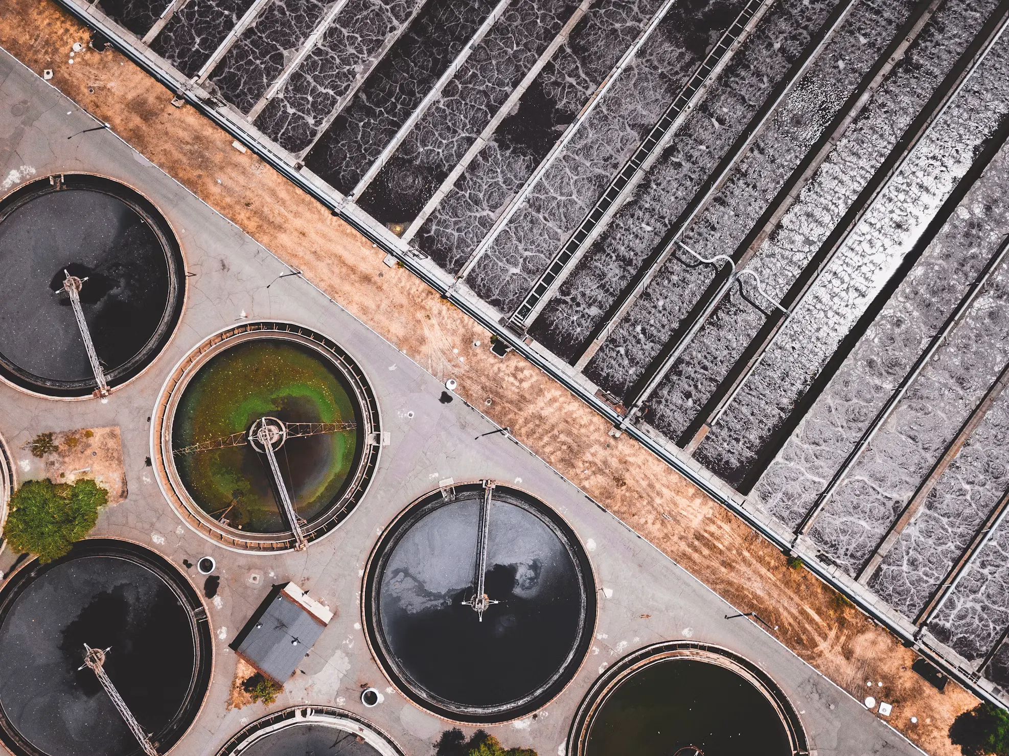 Aerial view of a water treatment plant, circular clarifier tanks and filter beds.